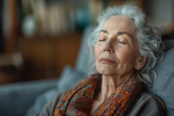 A peaceful image of a mature woman with closed eyes and relaxed features, resting on a soft gray sofa