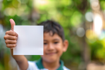 young boy holding up a white empty sign and giving his thumbs up