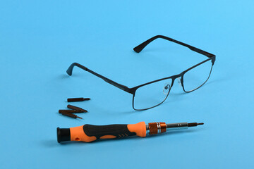 Set of screwdriver bits for repair reading glasses isolated on blue background.