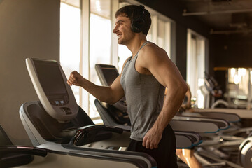 Male athlete exercising on treadmill at gym, man jogging, practicing sports on modern equipment in...