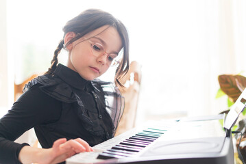 Portrait of a cute little girl playing the keyboard at home.
