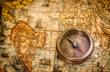 Vintage still life. Vintage compass lies on an ancient world map of 1565. Vintage style travel and adventure.