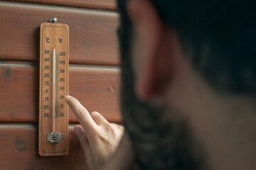 A man is checking the temperature with a thermometer.