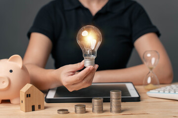 light bulb that shines in a hand on a pile of money. Innovative ideas for saving energy. Savings...