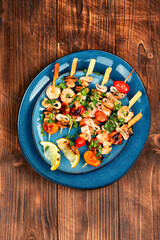 Seafood kebabs on wooden background.