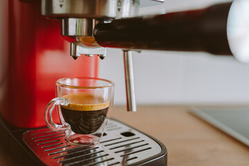 espresso coffee from coffee machine in transparent glass cup