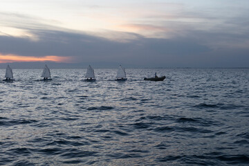 Choppy sea waters under a twilight sky with silhouettes of boats