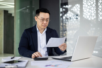 Professional Asian businessman reviewing documents in office