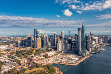 Fototapeta na wymiar Aerial view modern skyscrapers and buildings against near ocean and cloudy sky. Sydney, Australia.