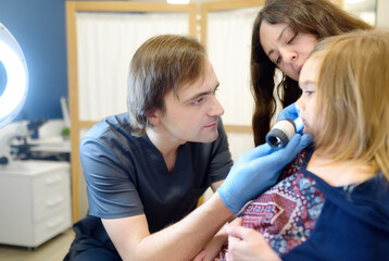 A caring doctor checks moles on the skin of a small child. A dermatologist looks at a rash on the neck of a girl using a dermatoscope. Baby at a pediatrician appointment