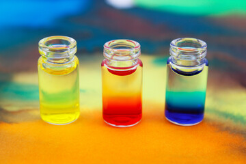 Glass bottles with red, yellow and blue ink on background with color stains