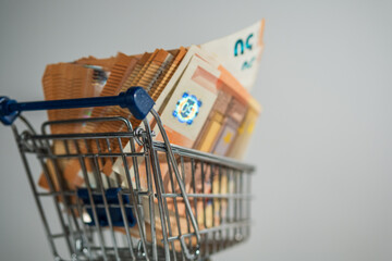 shopping cart loaded with 50 euro note bills white background 