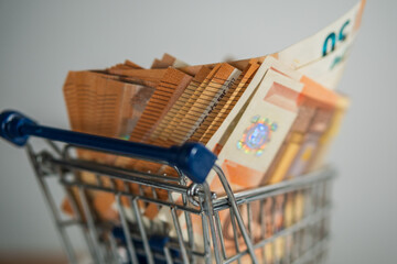shopping cart loaded with 50 euro note bills white background 