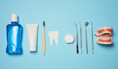 Mouthwash, toothpaste tube, dental floss and medical mirror on a blue background, oral hygiene.