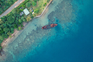 Abandoned broken sunken old ship that ran aground. Drone view. Tropical coast of Sanma, Vanuatu.