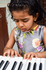 Asian cute girl playing the synthesizer or piano. Cute little kid learning how to play piano....