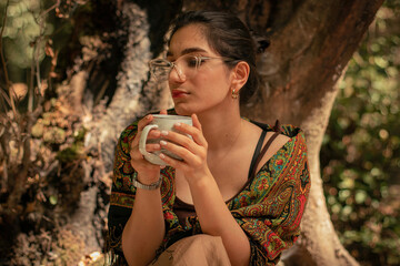 A village girl in nature thinking and drinking tea.