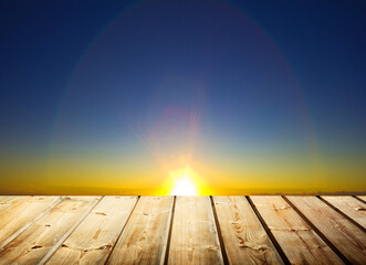 Wooden table with blue cloud background with light sunrise
