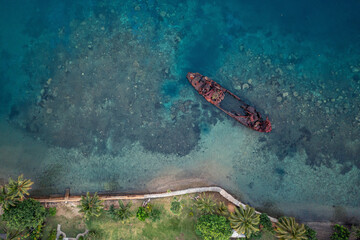 Top view of rusty wrecked boat in turquoise water near tropical shore. Drone photo. Sanma, Vanuatu.