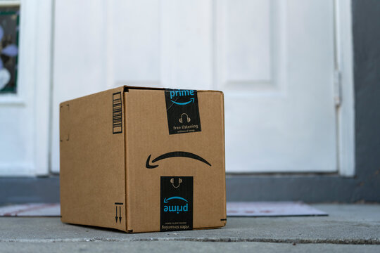 Amazon Prime package box with purchased online products delivered in front of house door. Amazon Prime priority delivery. E-commerce concept. Sarasota, USA - December 19, 2022.