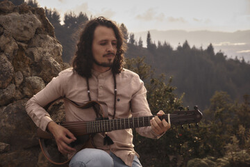 man playing guitar in the mountain