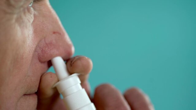 Close-up of an elderly man using a nasal spray to treat allergies and runny nose