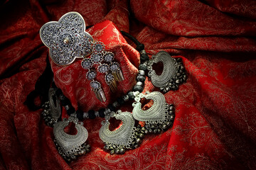 India ancient design accesories made by silver setting on India red textile.