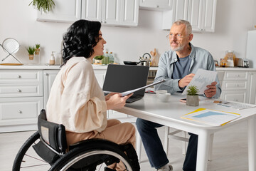 family budget of man and disabled woman reviewing documents at kitchen table