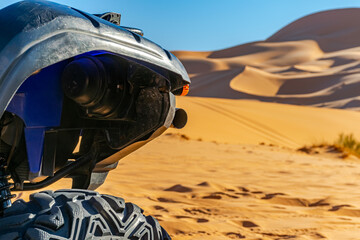A four wheeled quad front part blue and black color vehicle parked  in the Sahara desert, selective...