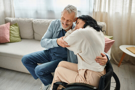 a disabled woman in a wheelchair embracing her husband with love and affection in a cozy living room setting.