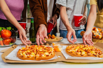 .Young Asian students gather with friends for a pizza party, laughing and sharing slices. Enjoying fast food delivery, they embody diversity and togetherness in a relaxed, enjoyable lifestyle.