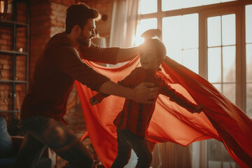 Father and son having fun playing with a red cape in the living room at home