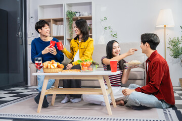 Young Asian friends gather in the living room, cheering and celebrating while watching a soccer match on TV. Their joy and togetherness exemplify the excitement of sports, friendship.