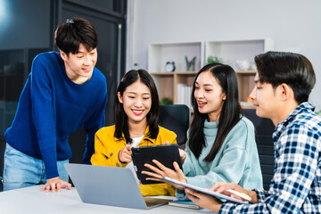 university classroom, diverse group of young students Asian collaborate study together, sharing smiles and insights around desks, exemplifying the joy of learning and friendship in higher education.