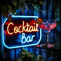 A neon sign for a cocktail bar with a glass of cocktail drink on a table