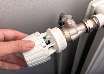 Woman Hand Adjusting The Knob Of Heating Radiator. The valve from the radiator - Heating. Hand adjusting thermostat valve of heating radiator in a room. Copy space.