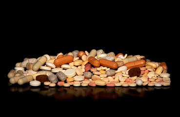 Close-up with a pile of different medicine tablets on a black background. Drug abuse