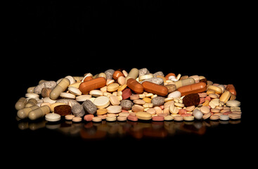 Close-up with a pile of different medicine pills on a black background