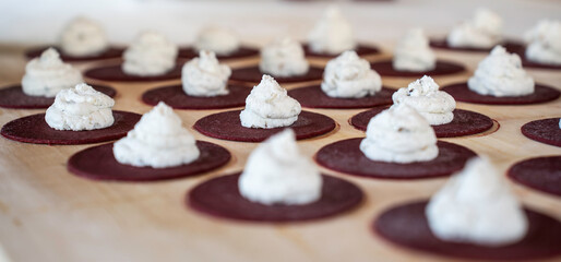 Beetroot bases for tortelli topped with ricotta peaks. The art of Italian cooking, captured in the delicate stage before union. Italian cuisine.