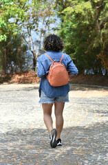 Chica de espaldas caminando por un sendero de piedra en un bosque Guatemalteco, cabello corto y rizado.