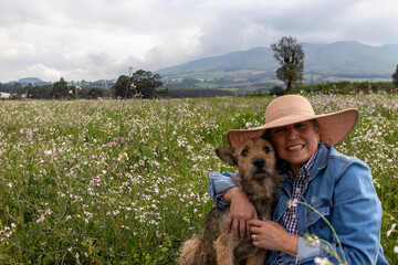 Adult female farmer enjoying a day in the field with her dog, adult woman hugging her dog