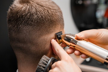 Barber shaves male client hair with sharp trimmer in barbershop closeup. Skilled hairstylist cuts man hair on occiput with machine in hairdressing salon