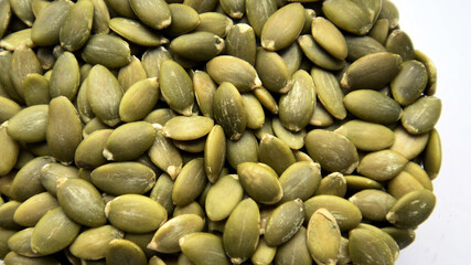 Organic green pumpkin seeds (hulled) on a white background
