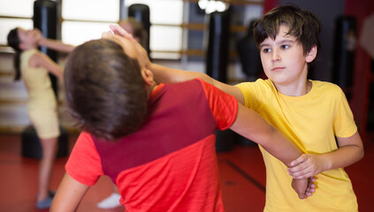 Fototapeta na wymiar Two boys in sparring practice self defense technique in the gym