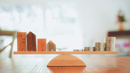 Wood house and Coins stack with balance scale. Money management, financial plan, time value of...