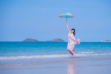 Happy sexy Asian traveller woman wear colorful beach dress umbrella and hat  show enjoys on tropical beach vacation in summer holidays
- 796759356