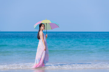 Happy sexy Asian traveller woman wear colorful beach dress umbrella and hat  show enjoys on tropical beach vacation in summer holidays
- 796759365
