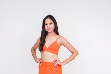 Young Asian woman in orange outfit posing confidently, isolated on white
