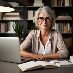 b'Portrait of a smiling mature woman sitting at her desk in a home office.'