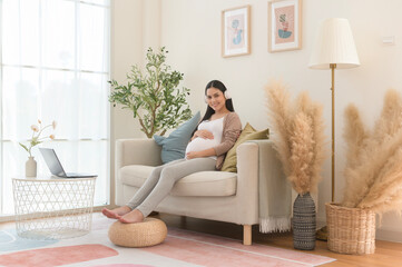 Happy pregnant woman with headphones listening to mozart music and lying on sofa, pregnancy concept